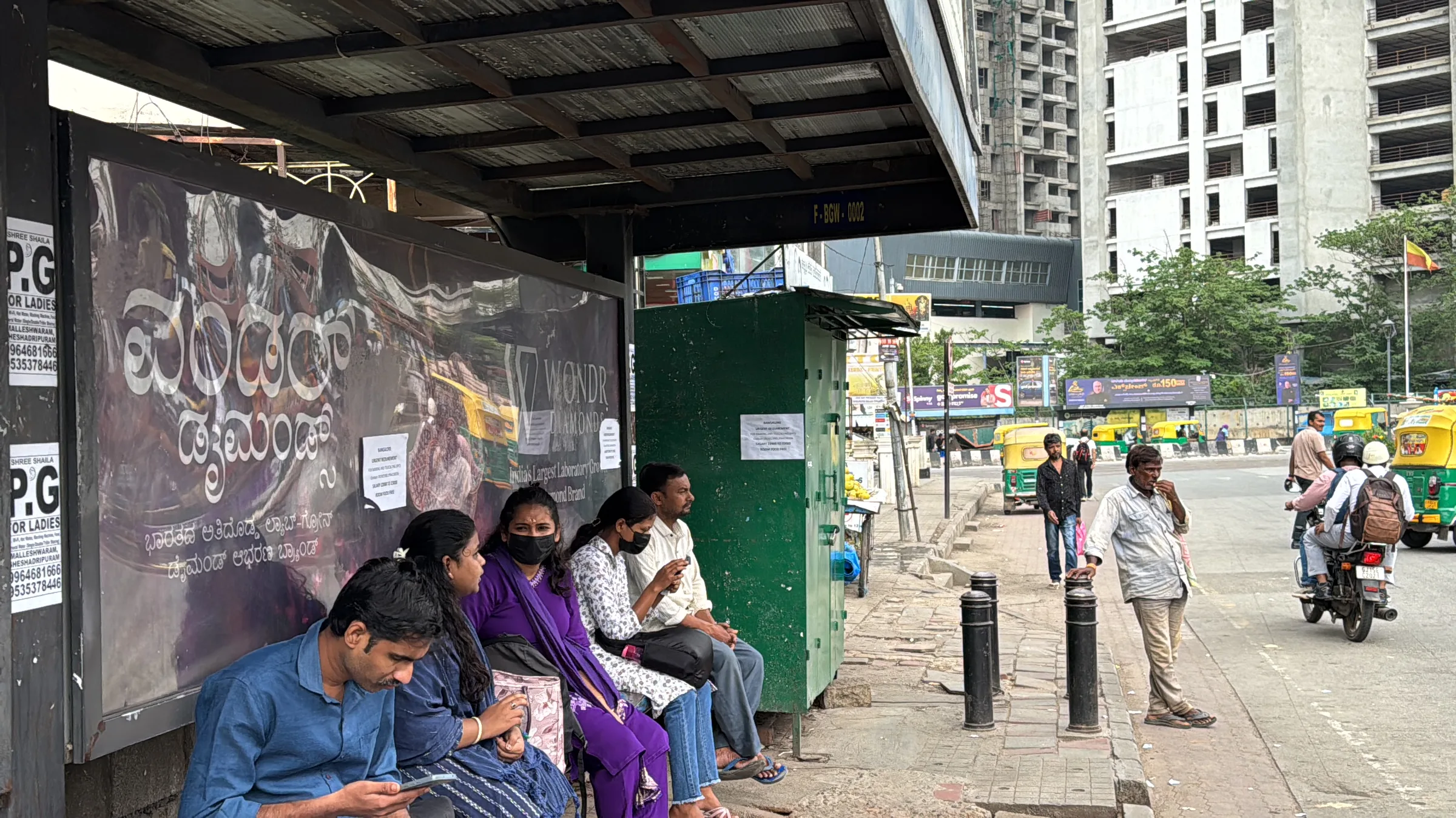Site photo: commuters waiting at the bus shelter, on their phones.