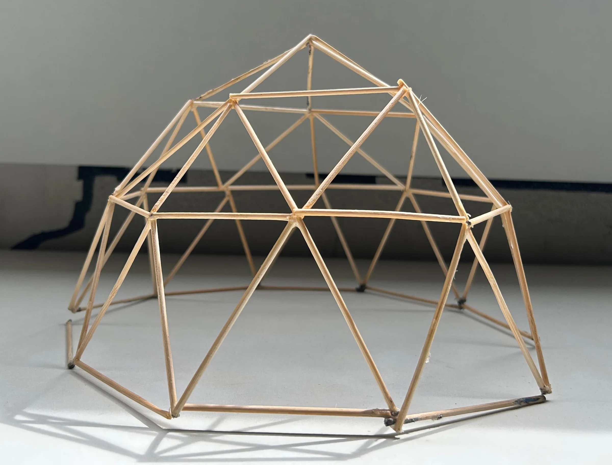 Geodesic dome stick model built from thin wooden sticks, front view.